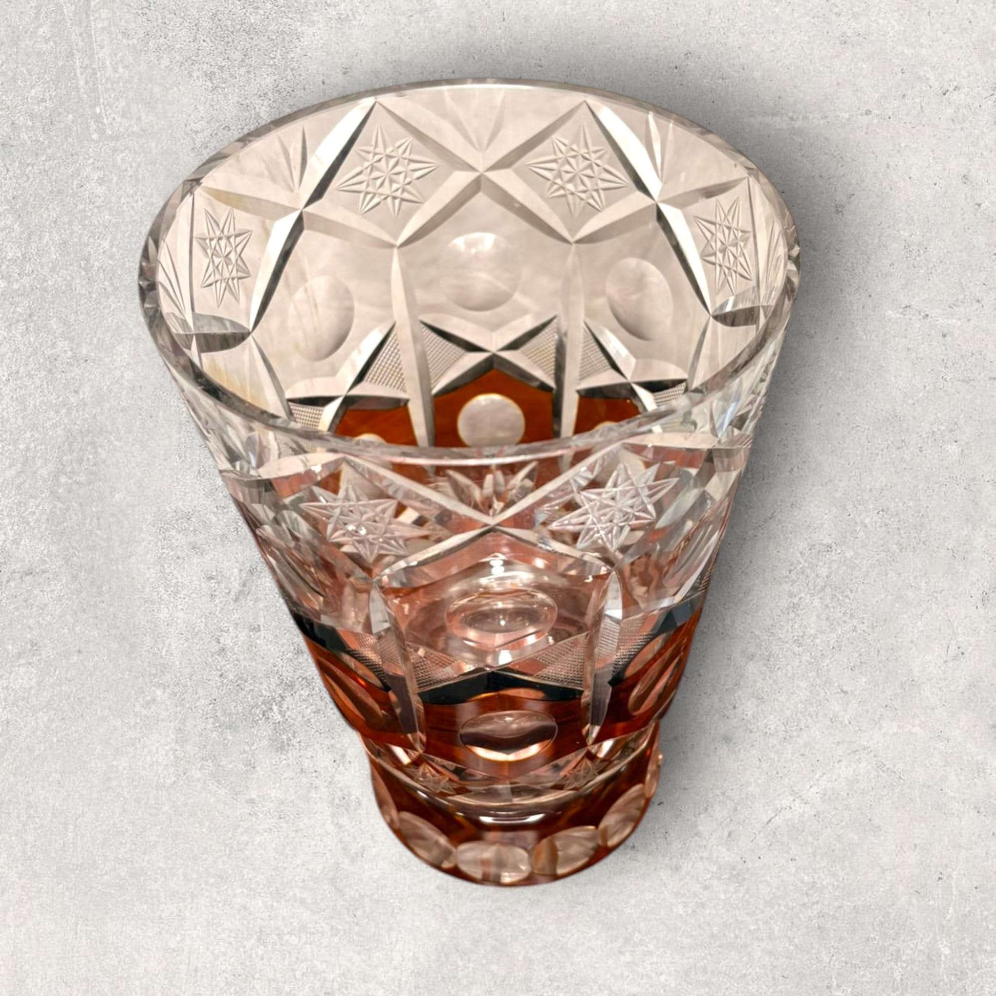 Su diseño combina cristal transparente tallado con franjas cálidas en ámbar, creando un contraste muy decorativo para vitrinas, aparadores, mesas auxiliares o espacios de interiorismo clásico y vintage.