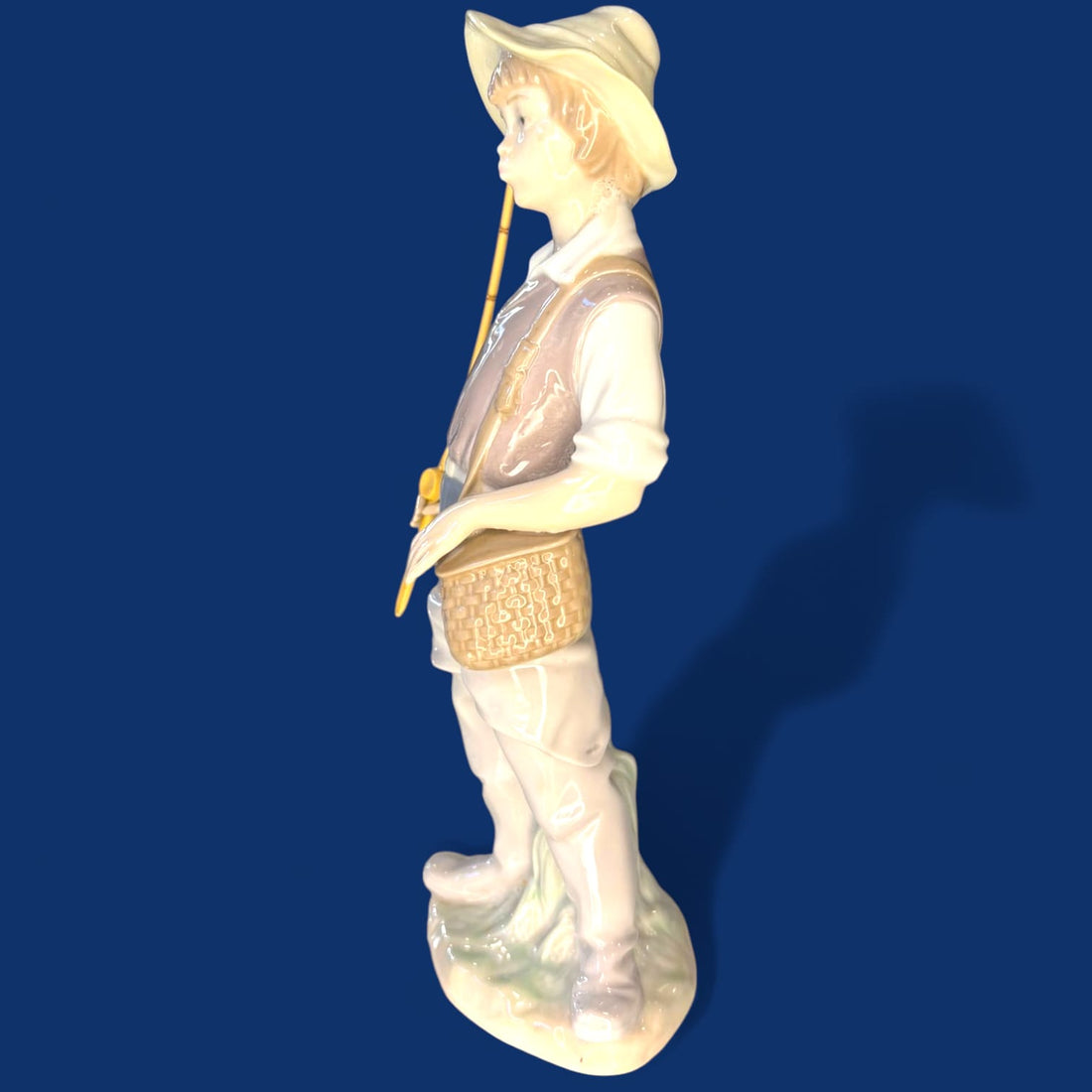 La encantadora figura “Fisher Boy” (Niño Pescador) de Lladró captura la inocencia y tranquilidad de la infancia con una delicada escena protagonizada por un joven pescador descansando junto a su caña.