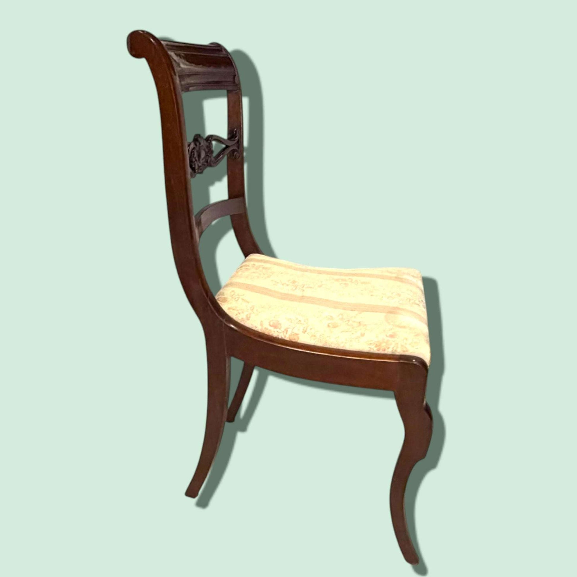 El diseño estilizado de estas sillas aporta sofisticación y armonía visual. Sus respaldos curvos incorporan una decoración tallada central de inspiración clásica, mientras que los asientos tapizados ofrecen comodidad y una estética cálida y acogedora.