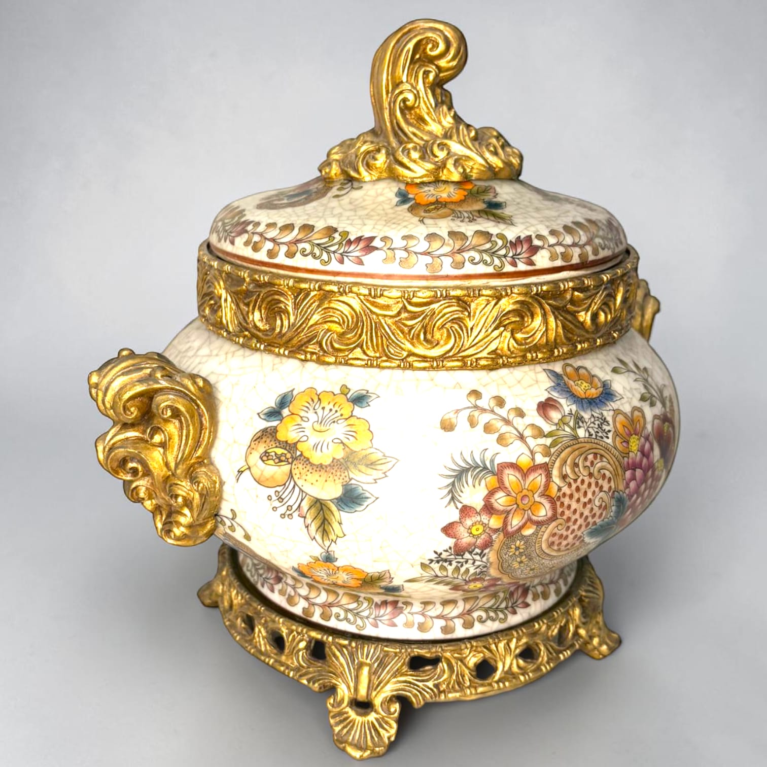 Formado por tres recipientes ornamentales con tapa, combina fondo marfil craquelado, motivos florales multicolor y relieves dorados de gran impacto visual.

Su función original es guardar joyas, pequeños recuerdos, bisutería, llaves, medallas o piezas delicadas. Hoy también destaca como objeto decorativo y de colección, ideal para vitrinas, tocadores, apar
