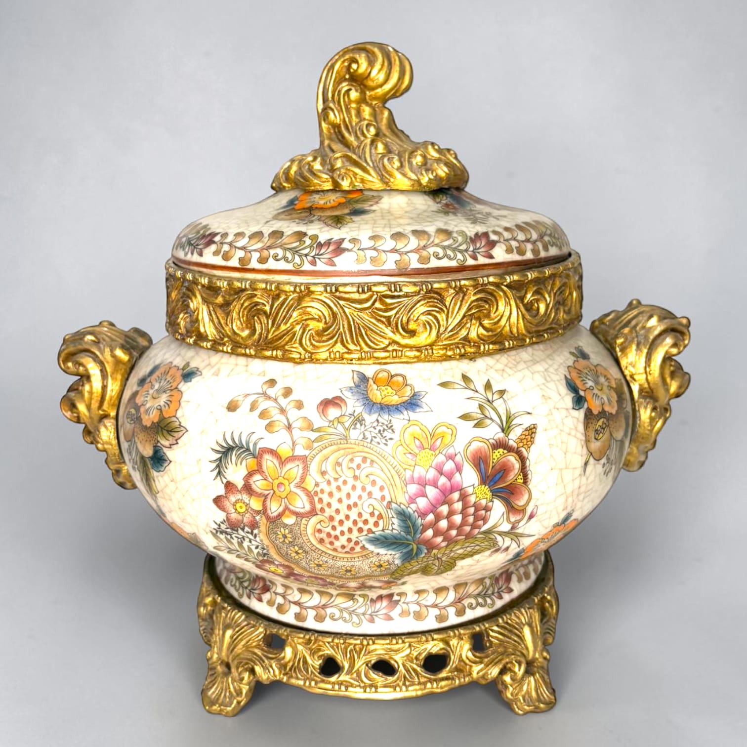 Formado por tres recipientes ornamentales con tapa, combina fondo marfil craquelado, motivos florales multicolor y relieves dorados de gran impacto visual.

Su función original es guardar joyas, pequeños recuerdos, bisutería, llaves, medallas o piezas delicadas. Hoy también destaca como objeto decorativo y de colección, ideal para vitrinas, tocadores, apar