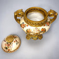 Formado por tres recipientes ornamentales con tapa, combina fondo marfil craquelado, motivos florales multicolor y relieves dorados de gran impacto visual.

Su función original es guardar joyas, pequeños recuerdos, bisutería, llaves, medallas o piezas delicadas. Hoy también destaca como objeto decorativo y de colección, ideal para vitrinas, tocadores, apar