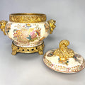 Formado por tres recipientes ornamentales con tapa, combina fondo marfil craquelado, motivos florales multicolor y relieves dorados de gran impacto visual.

Su función original es guardar joyas, pequeños recuerdos, bisutería, llaves, medallas o piezas delicadas. Hoy también destaca como objeto decorativo y de colección, ideal para vitrinas, tocadores, apar