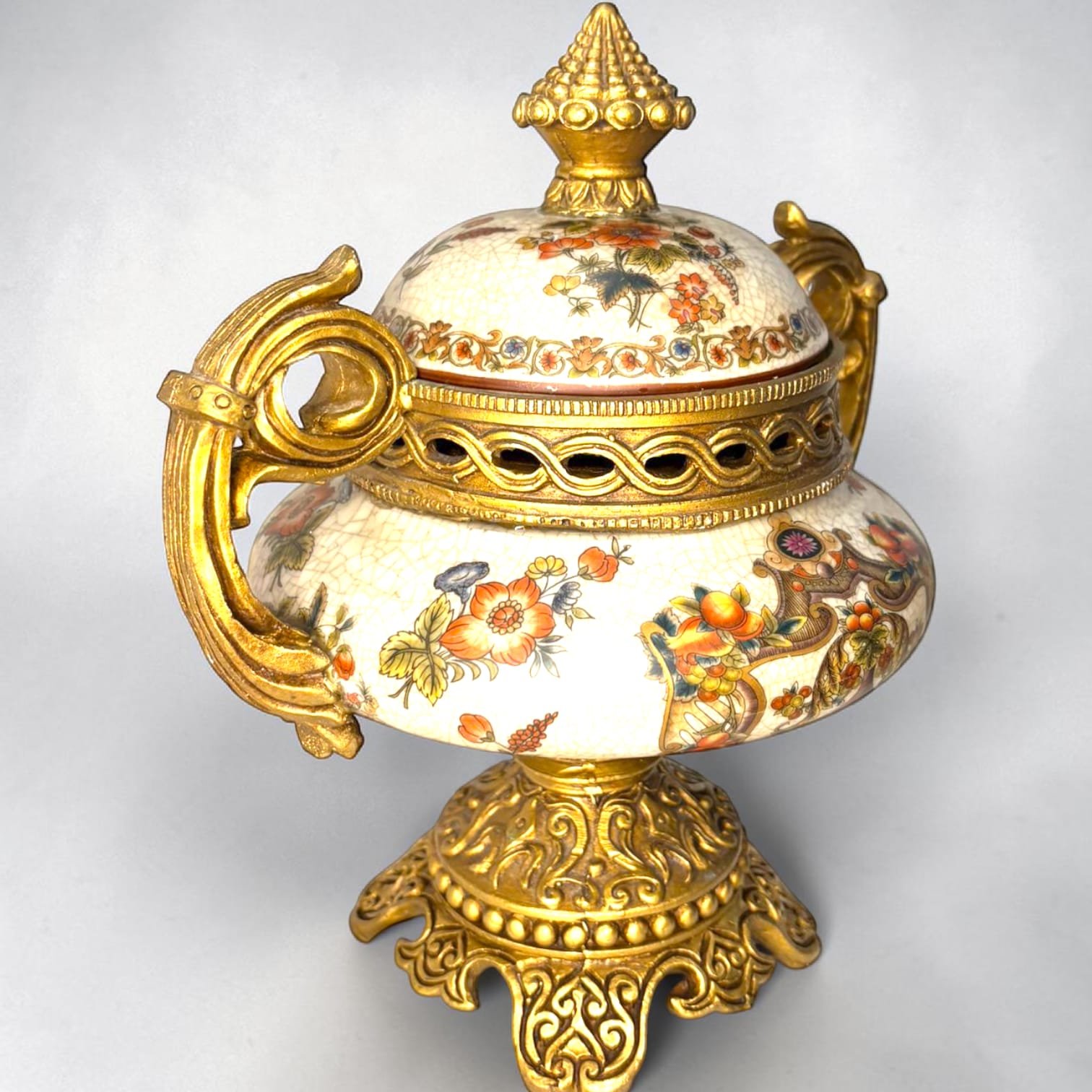 Formado por tres recipientes ornamentales con tapa, combina fondo marfil craquelado, motivos florales multicolor y relieves dorados de gran impacto visual.

Su función original es guardar joyas, pequeños recuerdos, bisutería, llaves, medallas o piezas delicadas. Hoy también destaca como objeto decorativo y de colección, ideal para vitrinas, tocadores, apar