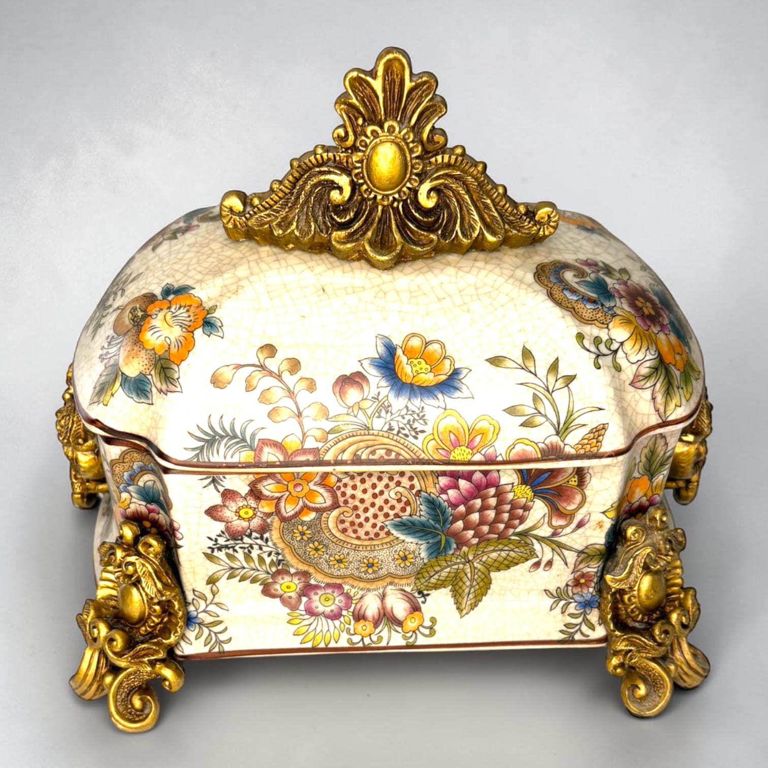 Formado por tres recipientes ornamentales con tapa, combina fondo marfil craquelado, motivos florales multicolor y relieves dorados de gran impacto visual.

Su función original es guardar joyas, pequeños recuerdos, bisutería, llaves, medallas o piezas delicadas. Hoy también destaca como objeto decorativo y de colección, ideal para vitrinas, tocadores, apar