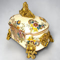 Formado por tres recipientes ornamentales con tapa, combina fondo marfil craquelado, motivos florales multicolor y relieves dorados de gran impacto visual.

Su función original es guardar joyas, pequeños recuerdos, bisutería, llaves, medallas o piezas delicadas. Hoy también destaca como objeto decorativo y de colección, ideal para vitrinas, tocadores, apar