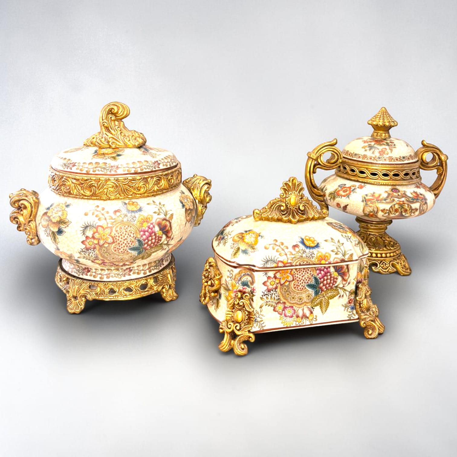 Formado por tres recipientes ornamentales con tapa, combina fondo marfil craquelado, motivos florales multicolor y relieves dorados de gran impacto visual.

Su función original es guardar joyas, pequeños recuerdos, bisutería, llaves, medallas o piezas delicadas. Hoy también destaca como objeto decorativo y de colección, ideal para vitrinas, tocadores, apar