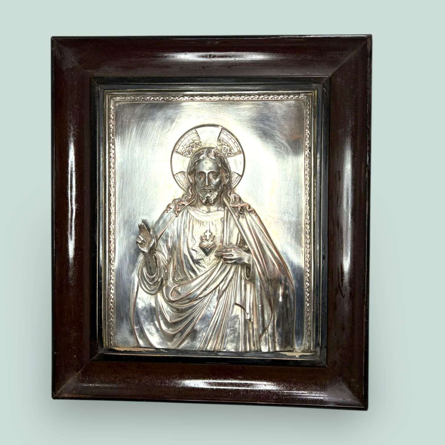 Este Relieve de Cristo Rey combina brillo, solemnidad y profundidad. La placa plateada aporta luz y presencia, mientras el marco de madera crea contraste y equilibrio. 