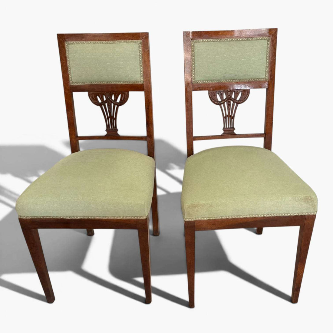 El tapizado verde tanto en el asiento como en el respaldo aporta confort visual y un atractivo contraste con la madera de tono cálido.