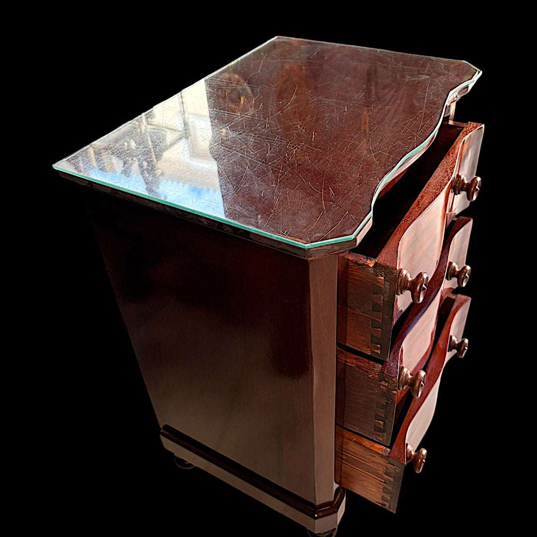 Su caoba, sus cajones ondulados y su tapa de cristal la convierten en una opción ideal para quien busca un mueble nuevo para su hogar, pero con historia y alma antigua.