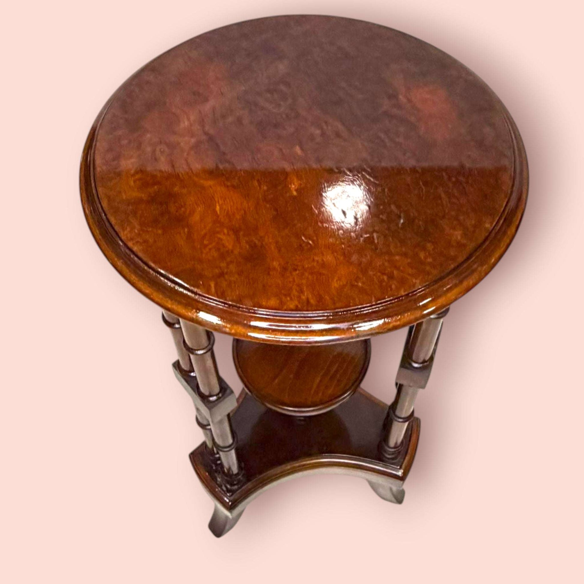 Estos Veladores destacan por una estructura muy original: tablero superior circular, columnas verticales decorativas y una pequeña repisa central que permite crear dos alturas de exposición. Esta repisa resulta perfecta para colocar una maceta con flores, una figura pequeña, una porcelana, una vela decorativa o un detalle especial, mientras que la parte superior puede utilizarse para una lámpara, un jarrón o una pieza protagonista.

En las imágenes se aprecia un acabado brillante de tono caoba cálido, con t