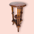 Estos Veladores destacan por una estructura muy original: tablero superior circular, columnas verticales decorativas y una pequeña repisa central que permite crear dos alturas de exposición. Esta repisa resulta perfecta para colocar una maceta con flores, una figura pequeña, una porcelana, una vela decorativa o un detalle especial, mientras que la parte superior puede utilizarse para una lámpara, un jarrón o una pieza protagonista.

En las imágenes se aprecia un acabado brillante de tono caoba cálido, con t