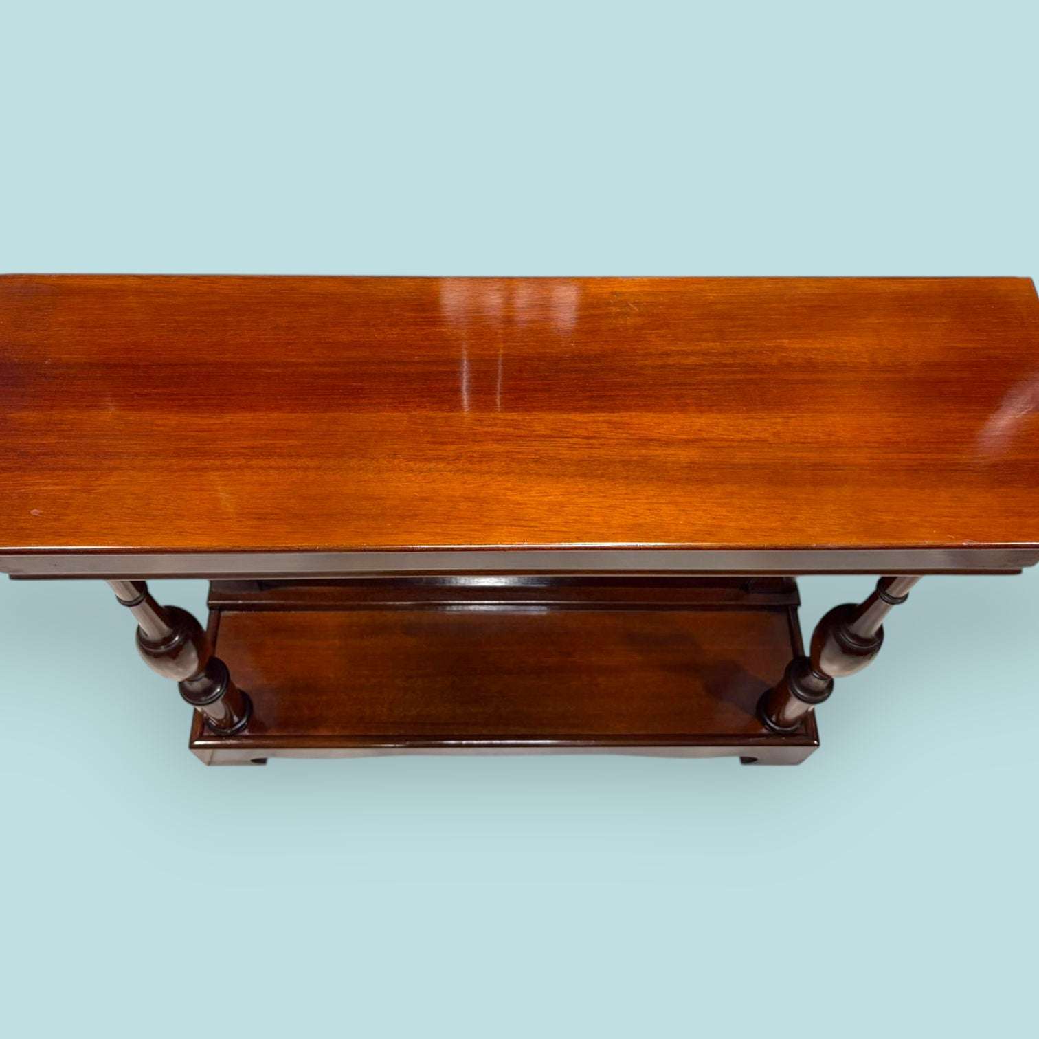 Esta Consola de caoba es una pieza auxiliar con gran valor decorativo, ideal para vestir recibidores, pasillos, salones, despachos o zonas de paso donde se busca un mueble estrecho, elegante y funcional. Su diseño alargado permite colocarla junto a una pared sin ocupar demasiado espacio, aportando calidez, orden y una estética clásica muy cuidada.

Su función original era servir como mueble de apoyo en entradas y salones, utilizado para colocar lámparas, jarrones, marcos, bandejas, llaves u objetos decorati