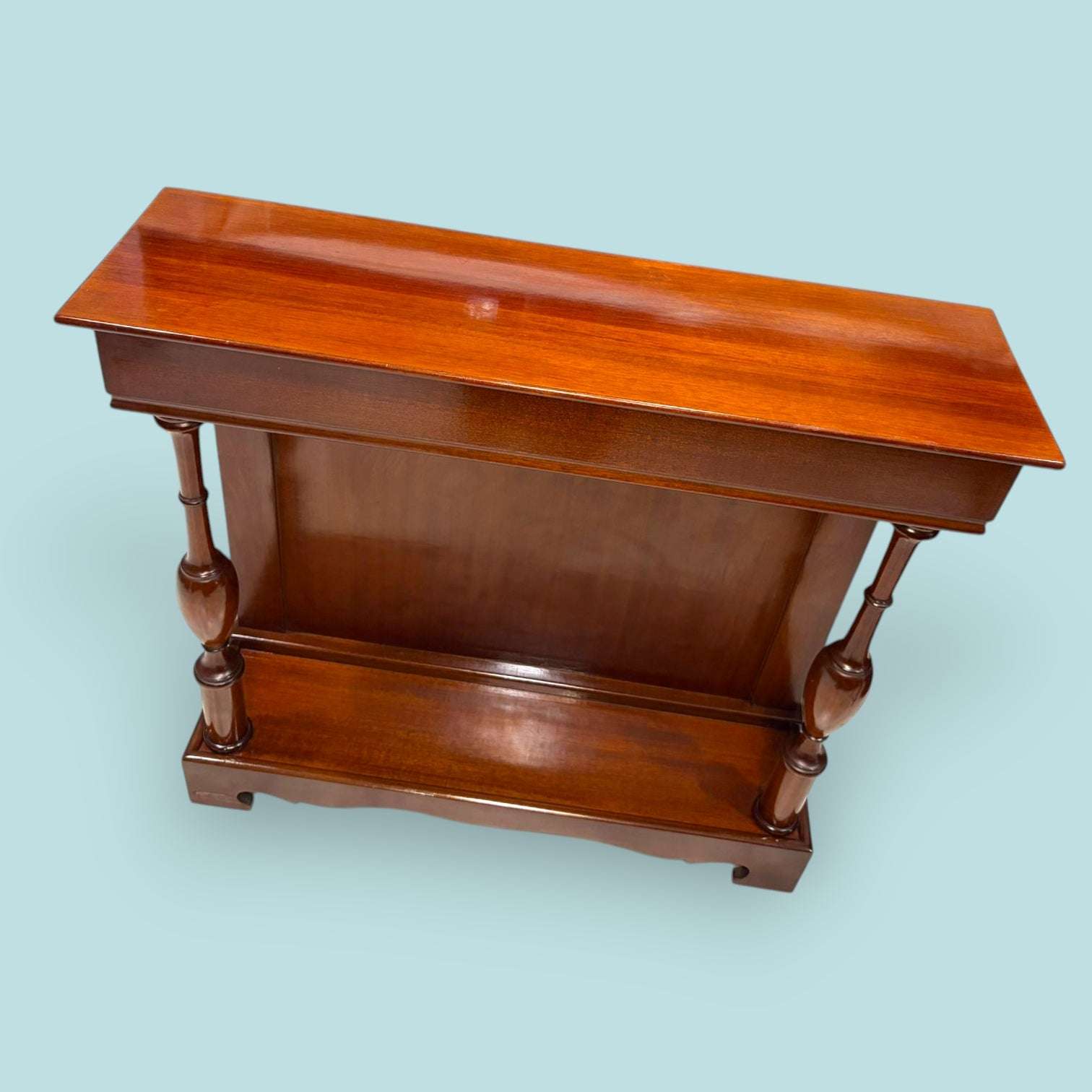 Esta Consola de caoba es una pieza auxiliar con gran valor decorativo, ideal para vestir recibidores, pasillos, salones, despachos o zonas de paso donde se busca un mueble estrecho, elegante y funcional. Su diseño alargado permite colocarla junto a una pared sin ocupar demasiado espacio, aportando calidez, orden y una estética clásica muy cuidada.

Su función original era servir como mueble de apoyo en entradas y salones, utilizado para colocar lámparas, jarrones, marcos, bandejas, llaves u objetos decorati