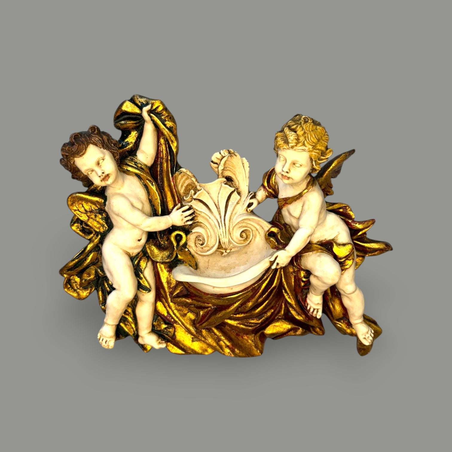 Esta benditera de resina representa una preciosa escena religiosa con dos ángeles en relieve, acompañando una pila central destinada tradicionalmente al agua bendita.