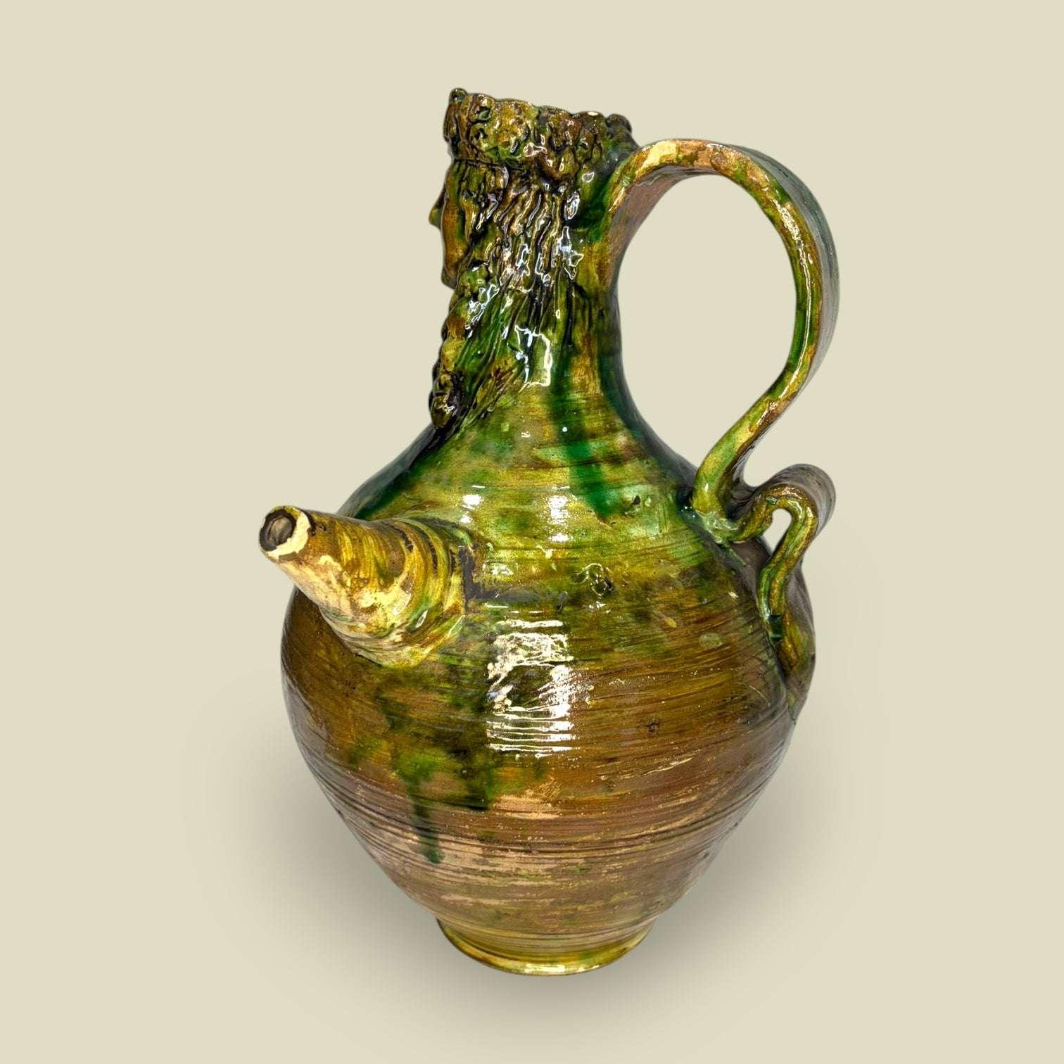 Botijo de cerámica con relieve de figura barbuda y acabado esmaltado en tonos verdes y ocres