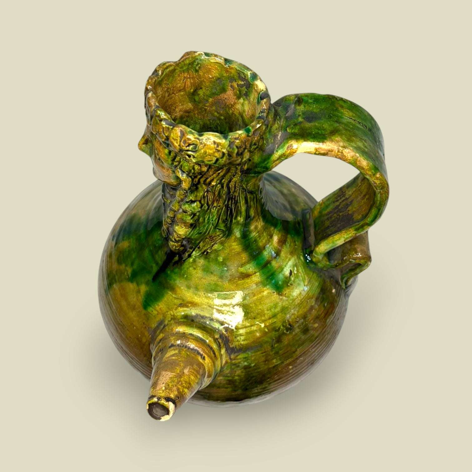Botijo de cerámica esmaltada con figura barbuda decorativa en tonos verdes y ocres