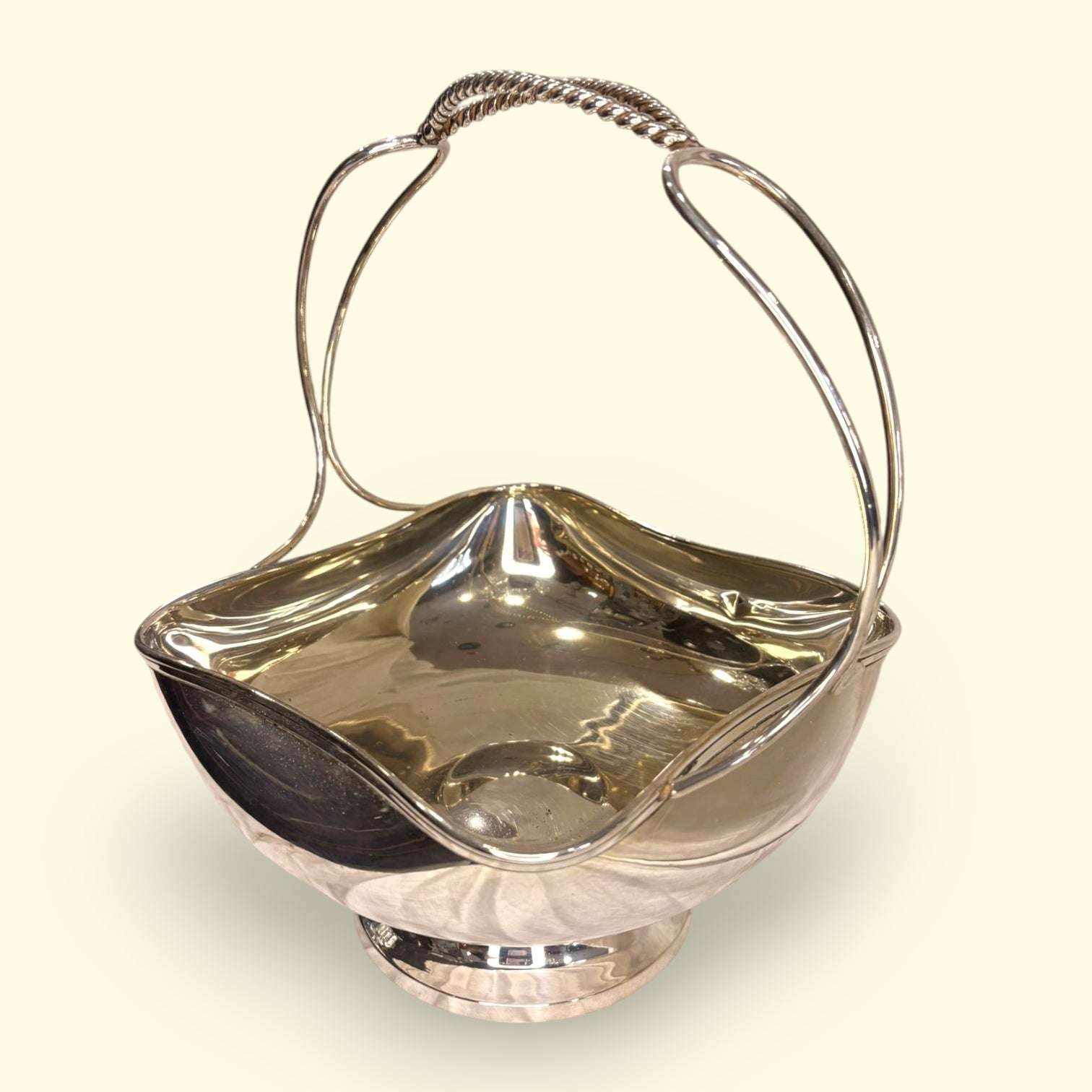 Este Centro de mesa de metal plateado es una pieza elegante, luminosa y muy versátil, diseñada con forma de cesta y asa superior para facilitar su transporte y colocación. 