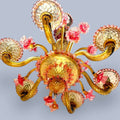 Esta magnífica lámpara destaca por sus delicados detalles florales en tonos rosados, realizados artesanalmente en cristal, combinados con elegantes brazos curvados y tulipas decoradas en tonos ámbar dorado que crean una iluminación cálida y acogedora.