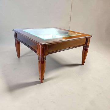 Elegante Mesa baja de salón realizada en madera de caoba, una pieza clásica y refinada que destaca por sus líneas equilibradas, su excelente presencia decorativa y su sofisticado cristal biselado central.