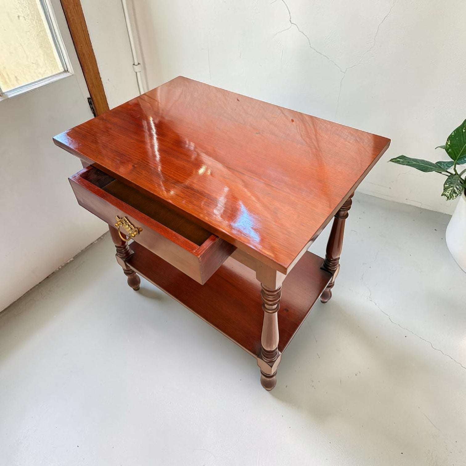 Su diseño rectangular, su acabado brillante y sus proporciones equilibradas la convierten en una opción ideal para salones, recibidores, dormitorios, despachos o rincones donde se necesita una superficie auxiliar con estilo.

Su función original fue servir como mesa de apoyo para colocar objetos de uso diario, lámparas, libros, piezas decorativas o pequeños elementos personales. Hoy 