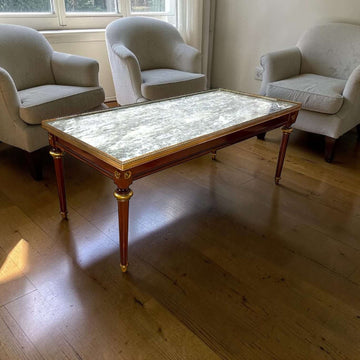 Esta Mesa baja de salón combina tres elementos que siempre elevan una estancia: caoba, mármol oscuro y detalles metálicos dorados. 