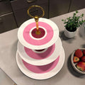 Compuesto por tres platos de porcelana en distintos tamaños y unidos mediante una estructura de metal dorado, destaca por su diseño sofisticado y su estética vintage con un aire muy especial.