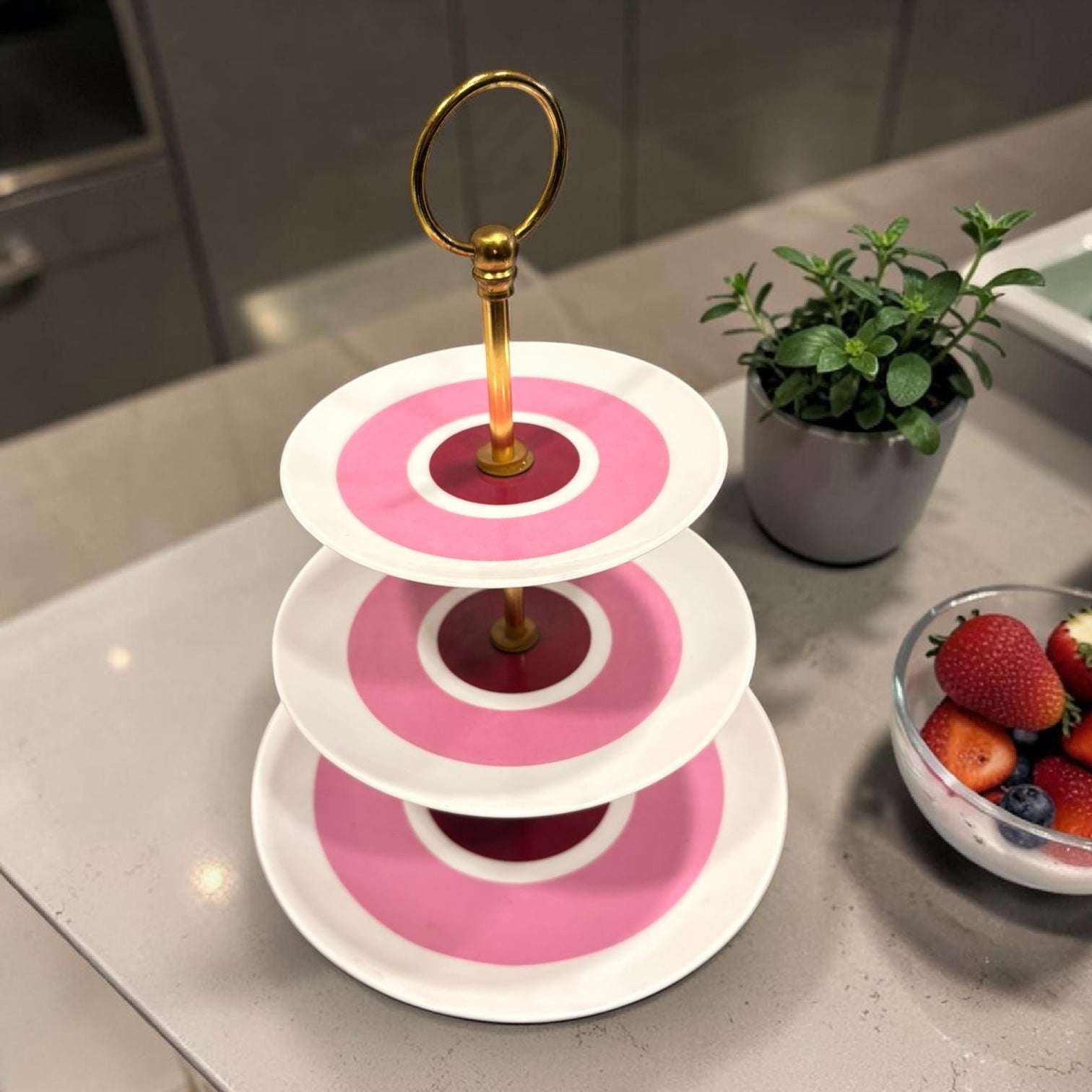 Compuesto por tres platos de porcelana en distintos tamaños y unidos mediante una estructura de metal dorado, destaca por su diseño sofisticado y su estética vintage con un aire muy especial.

