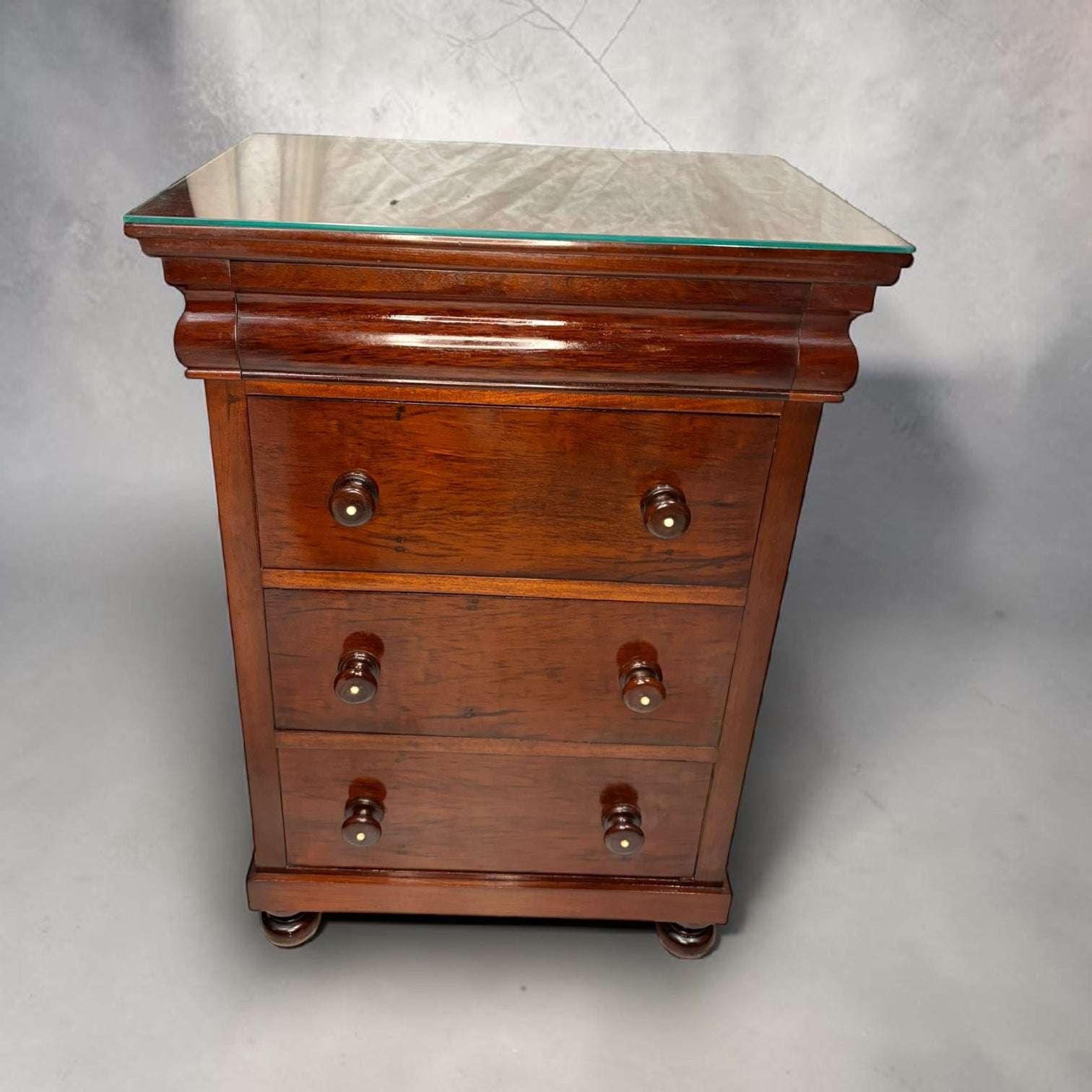 Su función original es acompañar la cama como mueble auxiliar de dormitorio, ofreciendo espacio para guardar objetos personales, libros, documentos, accesorios o pequeños enseres del día a día. 