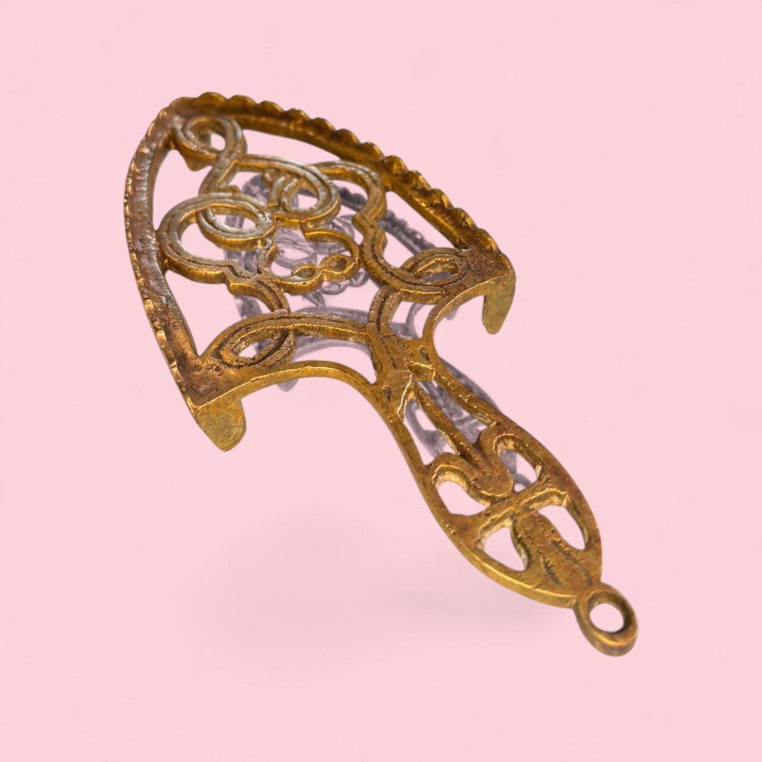 Este Descansadero destaca por su diseño calado, elegante y ornamental. Su estructura presenta formas curvas, motivos simétricos y una silueta alargada que recuerda a los antiguos soportes domésticos utilizados en tareas de planchado. 