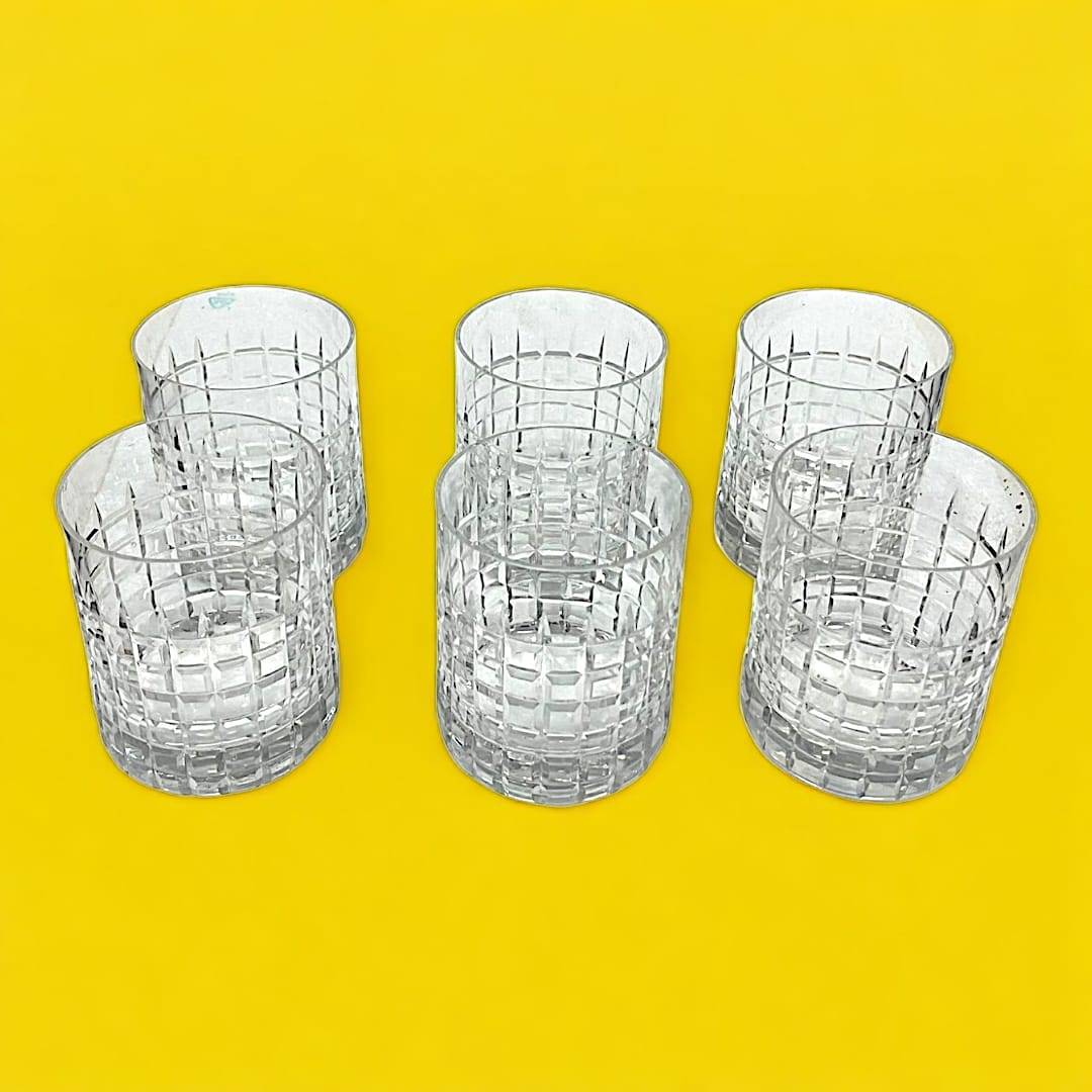 Seis vasos de cristal con patrón cuadriculado, juego decorativo que acompaña la coctelera con tapa de plata para eventos sofisticados.