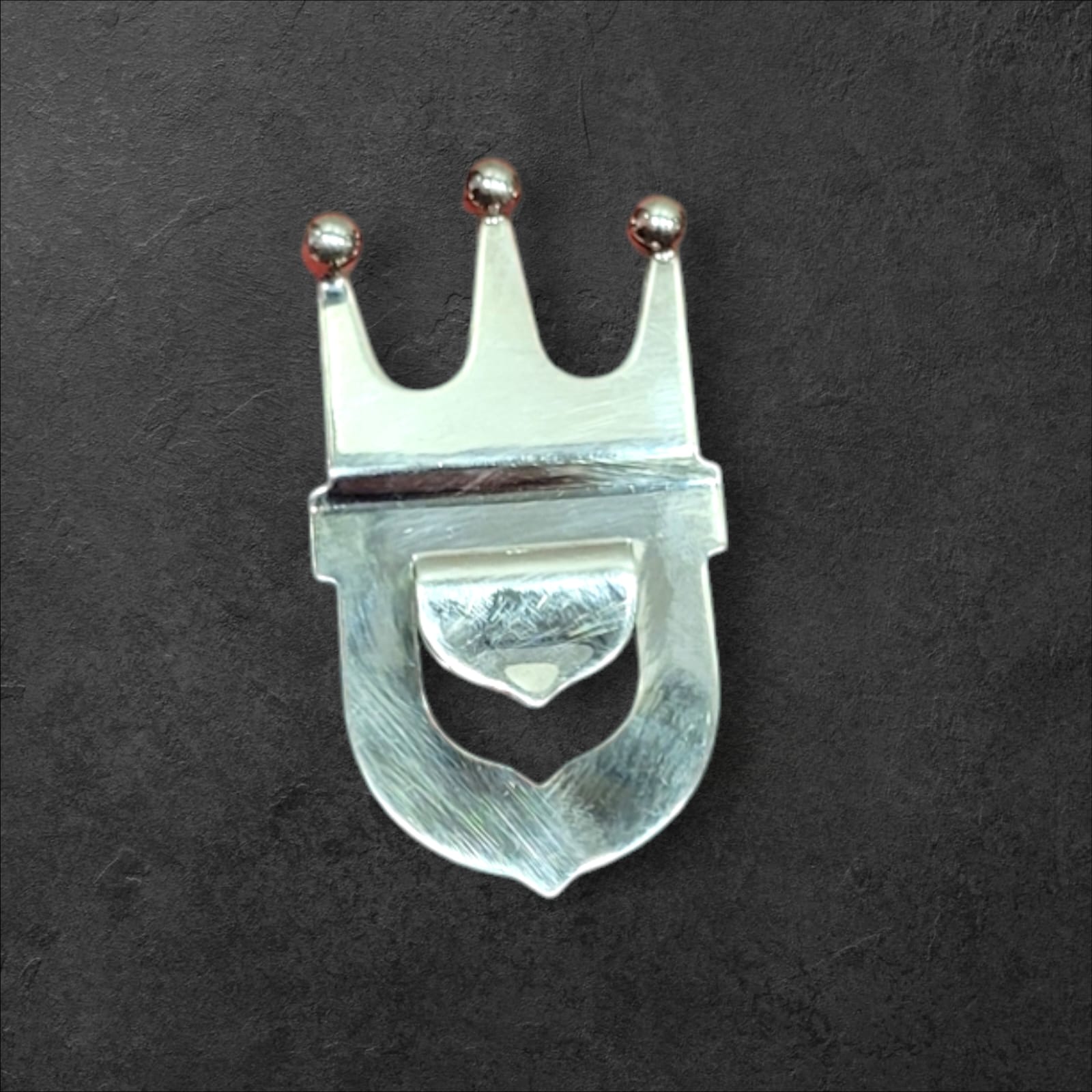 Abrebotellas de metal plateado con diseño de corona, estilo vintage, ideal para decoración y uso en bares o cocinas elegantes.