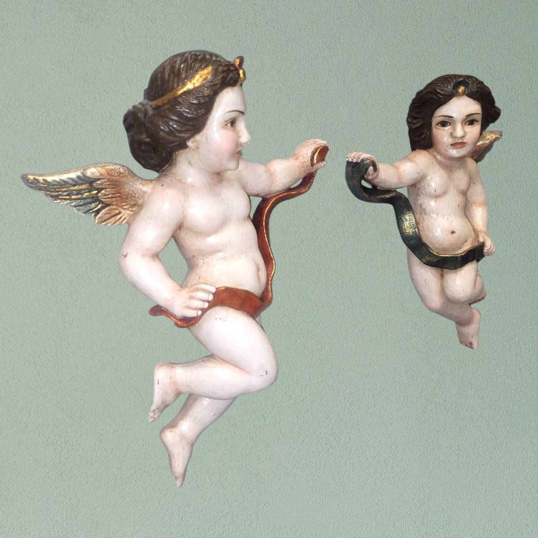 Vista frontal de la pareja de ángeles tallados en madera, mostrando sus detalles artesanales.
