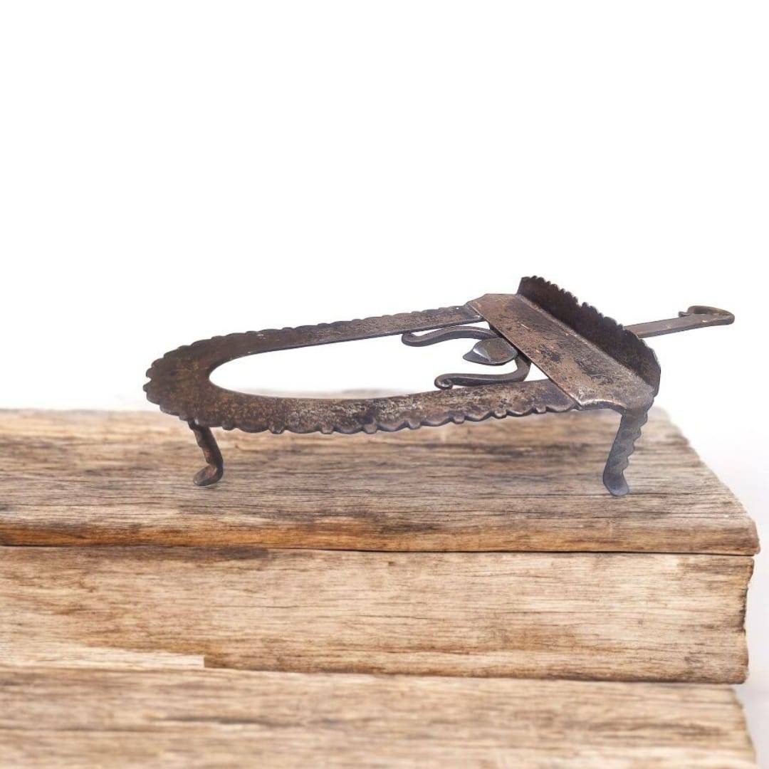 Descansa plancha hierro forjado con patas curvas y borde dentado, pieza funcional y decorativa para ambientes con estilo antiguo.