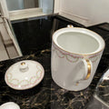 Tarro de porcelana fina francesa abierto, mostrando interior blanco y asas doradas, con tapa decorada con rosas y detalles dorados. Perfecto para coleccionistas.
