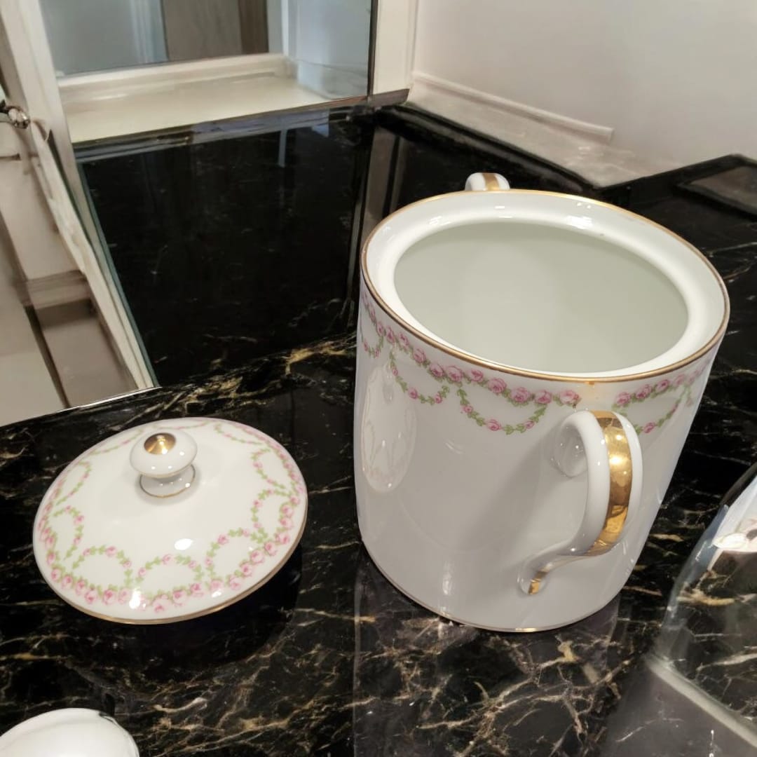 Tarro de porcelana fina francesa abierto, mostrando interior blanco y asas doradas, con tapa decorada con rosas y detalles dorados. Perfecto para coleccionistas.