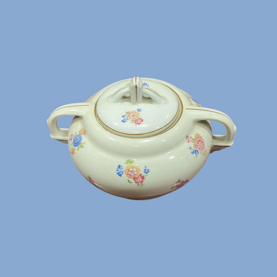 Azucarero Victoria de porcelana con tapa y asas, decoración floral en tonos pastel, ideal para ambientar mesas con elegancia y tradición.