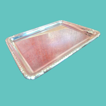 Bandeja de metal plateado con ornamentos elegantes y marco repujado clásico, ideal para decoración de interiores en estilo vintage.