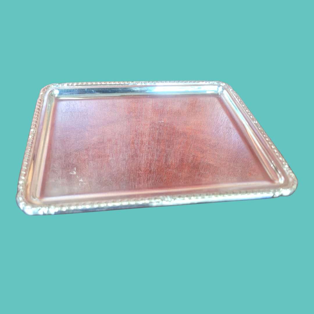 Bandeja de metal plateado con acabado espejo y borde decorativo, perfecta para uso ornamental en el hogar o jardín.