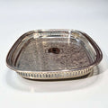 Bandeja de metal plateada grabada, elegante y artesanal con diseño floral y bordes calados, ideal para decoración de interiores refinada.