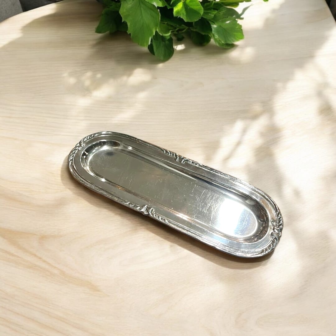 Bandeja decorativa de metal plateado con bordes detallados. Aporta elegancia y funcionalidad a cualquier ambiente del hogar.