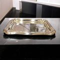 Bandeja de metal plateado con bordes ondulados y acabado brillante. Perfecta para uso decorativo en interiores sofisticados.