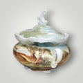 Bombonera de porcelana fina pintada a mano con paisajes campestres, asas decorativas y base elevada. Ideal para regalo o decoración.