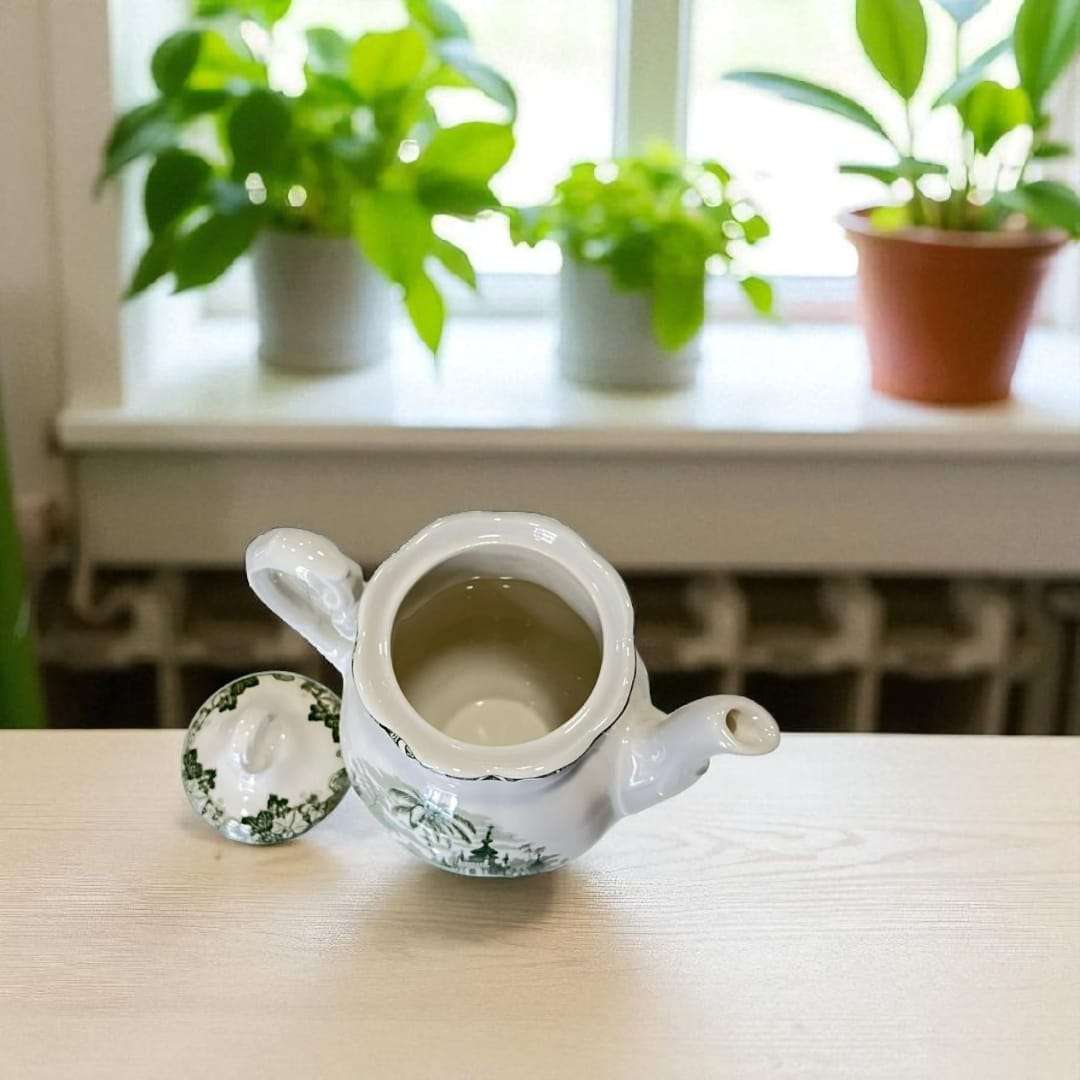 Fotografía lateral de la cafetera, destacando su forma abombada y decoración clásica en verde.
