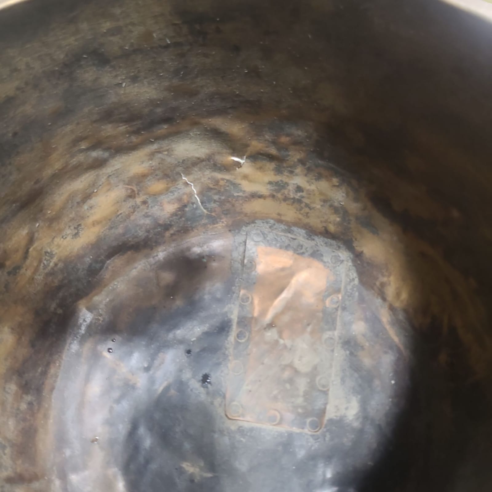 Primer plano de las reparaciones del caldero, evidenciando su uso prolongado y carácter único.