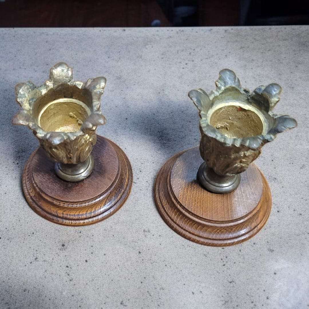 Pareja de candeleros sobre superficie gris, resaltando el trabajo artesanal.