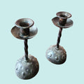Candeleros artesanales de hierro forjado con diseño rústico y textura martillada. Accesorio decorativo para mesa o repisa en casa de campo.