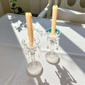 Candeleros de cristal antiguos sobre mesa blanca iluminada por el sol, pieza decorativa clásica para interiores con estilo refinado.