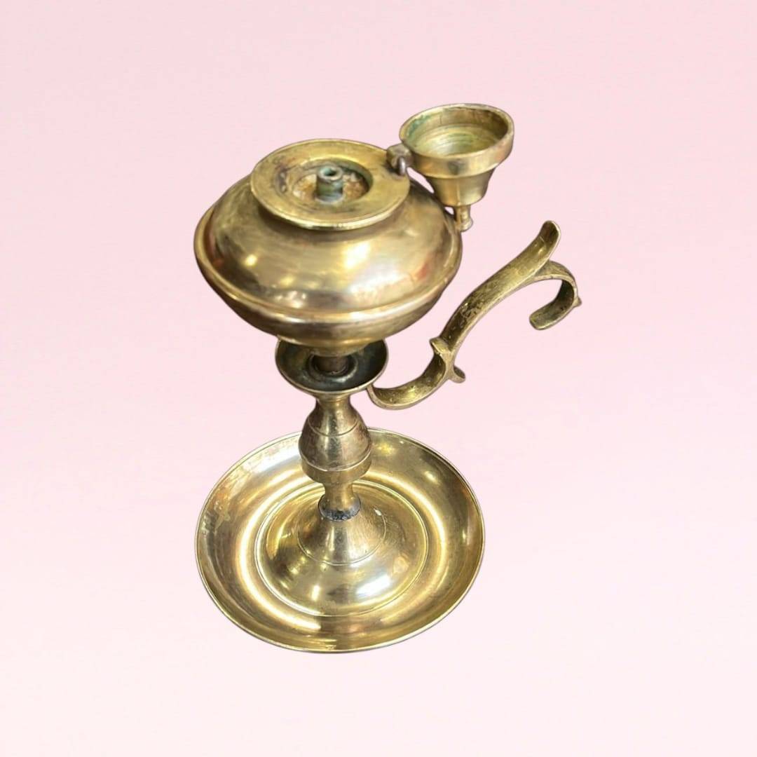 Candil metálico vintage de colección en bronce con depósito para aceite y asa ornamentada. Ideal para decoración retro en hogar o jardín.