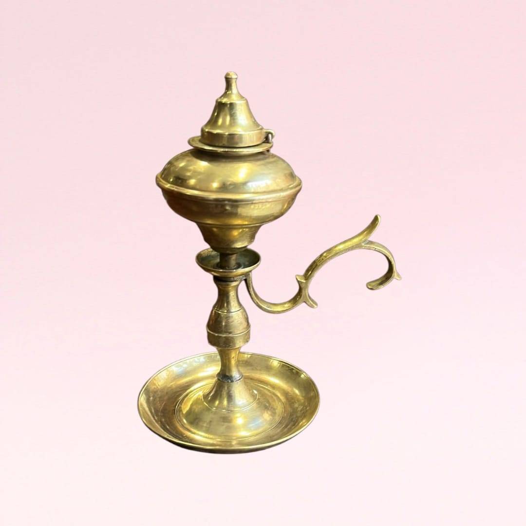 Candil metálico vintage de colección en bronce con depósito para aceite y asa ornamentada. Ideal para decoración retro en hogar o jardín.